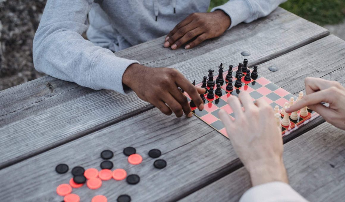 anonymous diverse men playing chess game in park