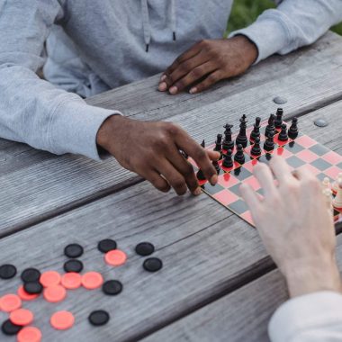 anonymous diverse men playing chess game in park