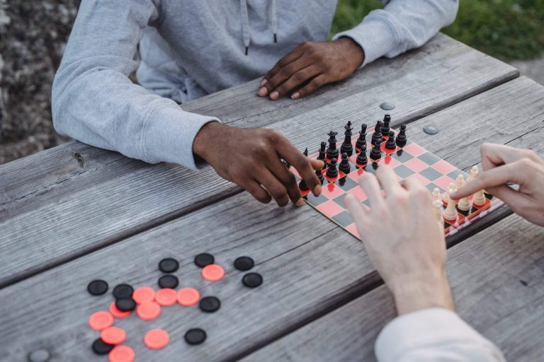 anonymous diverse men playing chess game in park