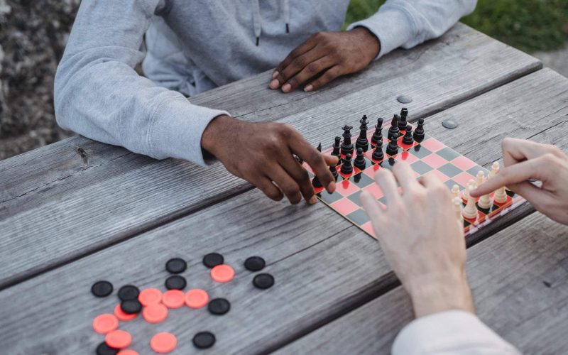 anonymous diverse men playing chess game in park