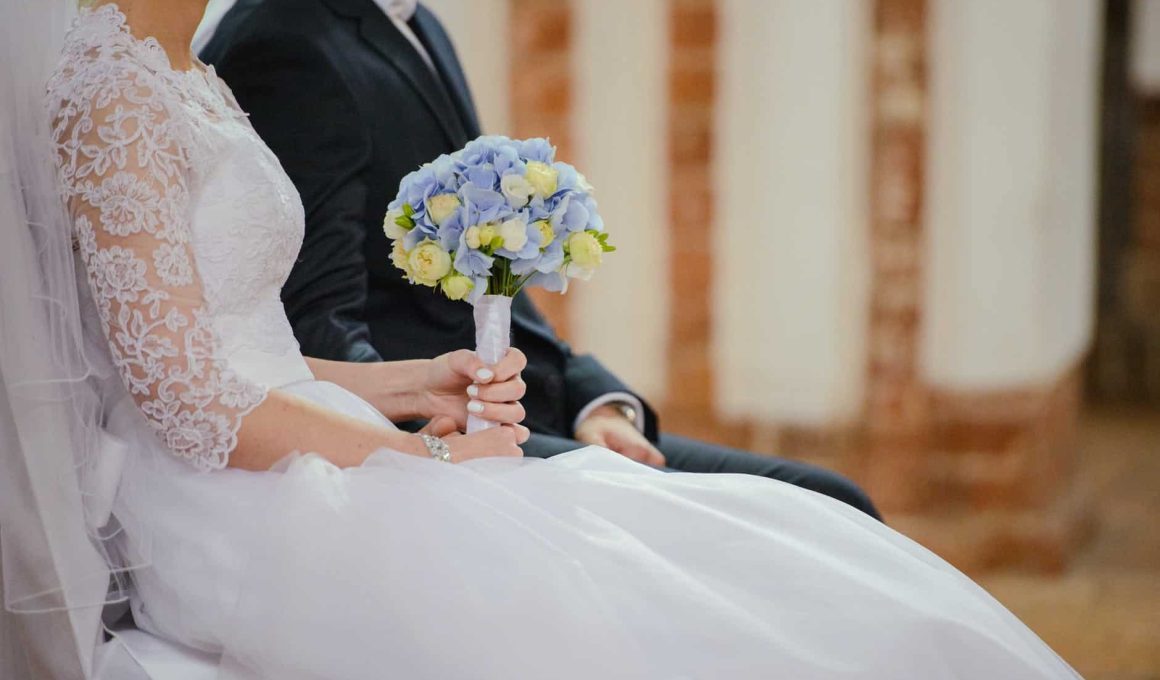 unrecognizable young newlyweds sitting together during wedding celebration