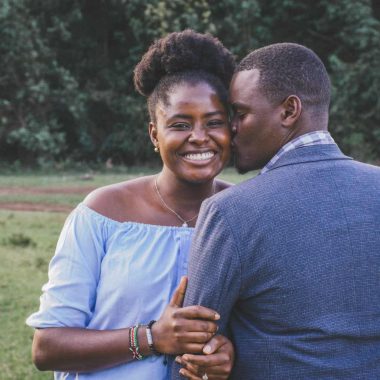 man kissing left cheek of smiling woman