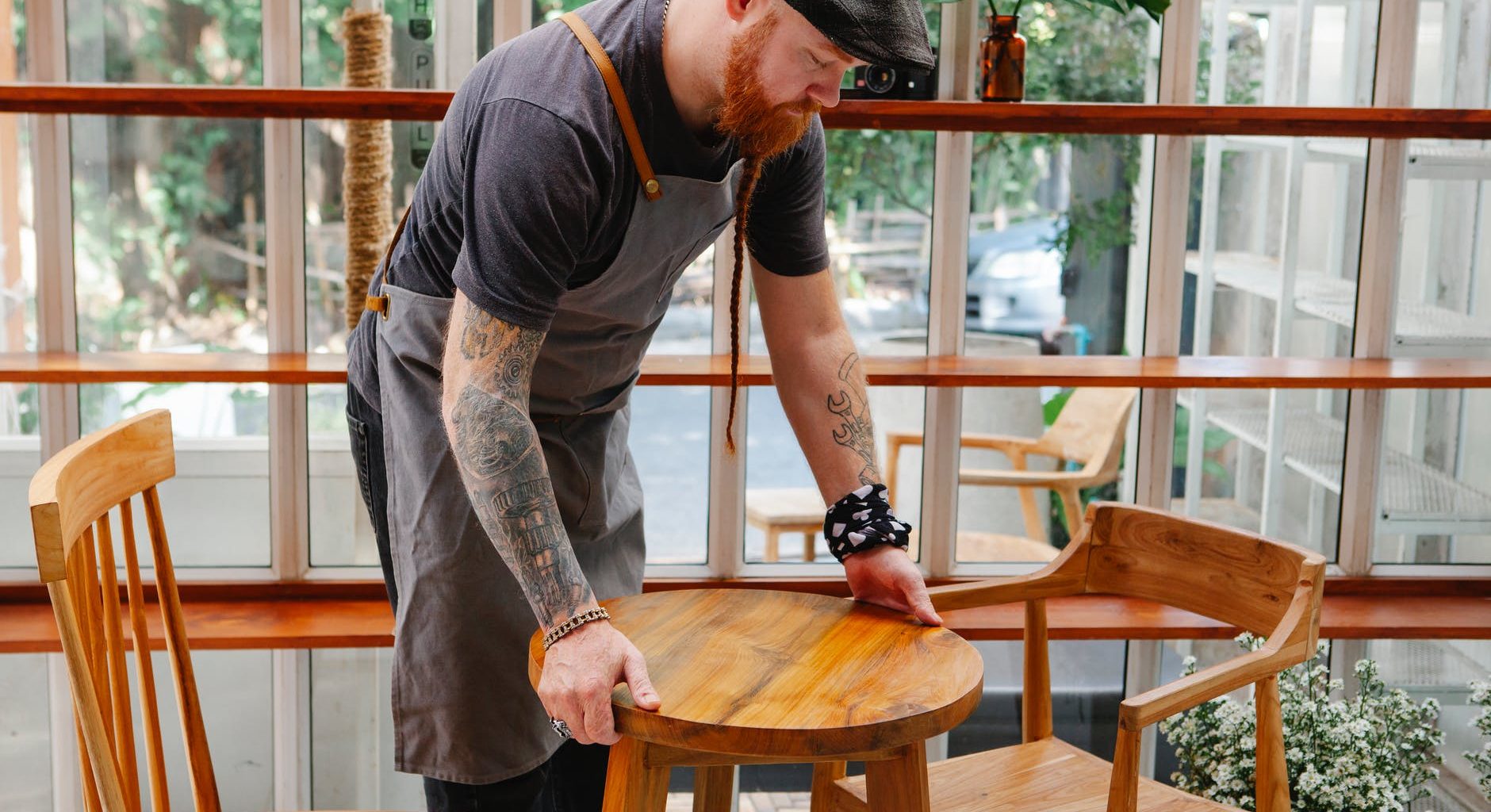 crop cafeteria worker with tattoos putting table on floor