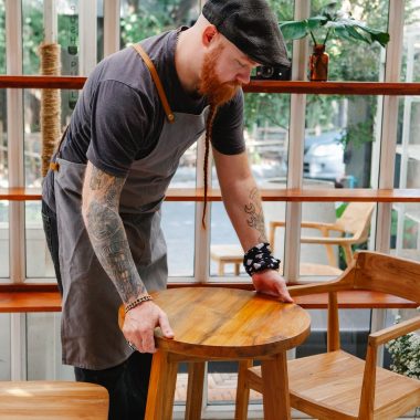 crop cafeteria worker with tattoos putting table on floor