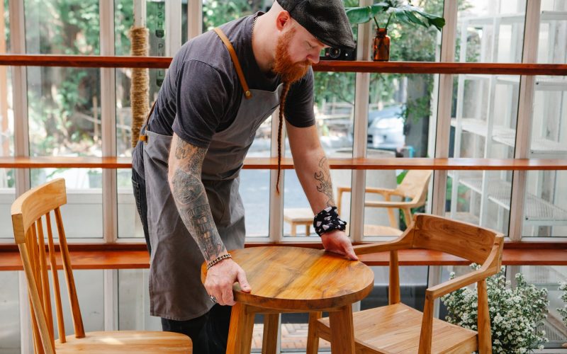 crop cafeteria worker with tattoos putting table on floor