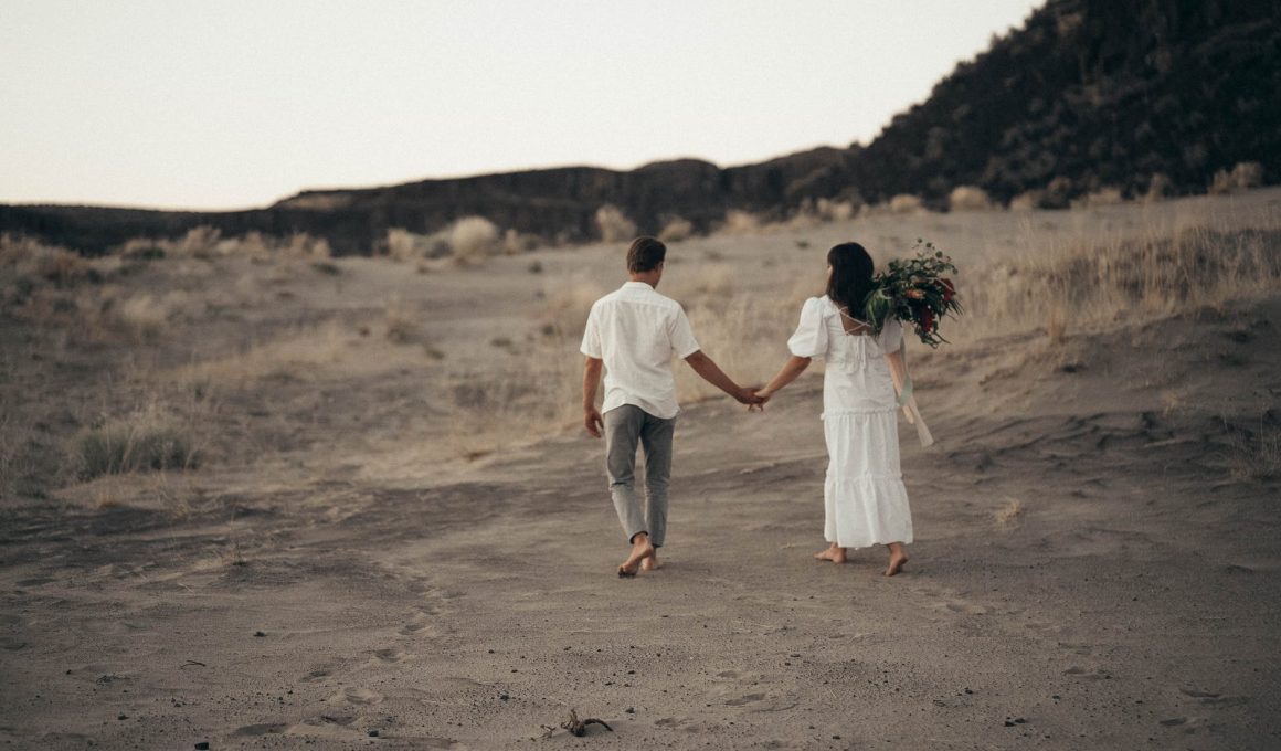 unrecognizable wedding barefoot couple walking on sandy terrain