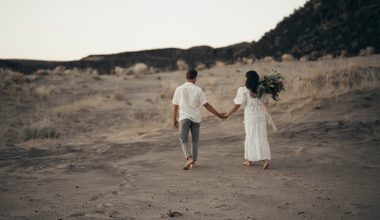 unrecognizable wedding barefoot couple walking on sandy terrain