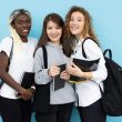 joyful diverse female students standing with books in studio