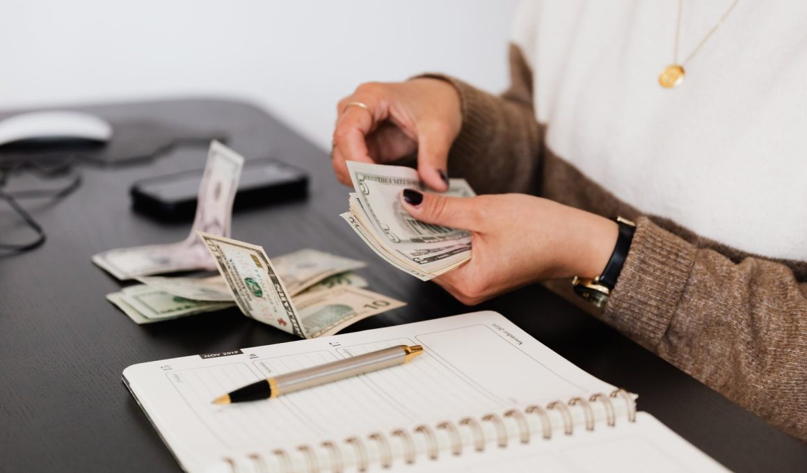 crop payroll clerk counting money while sitting at table