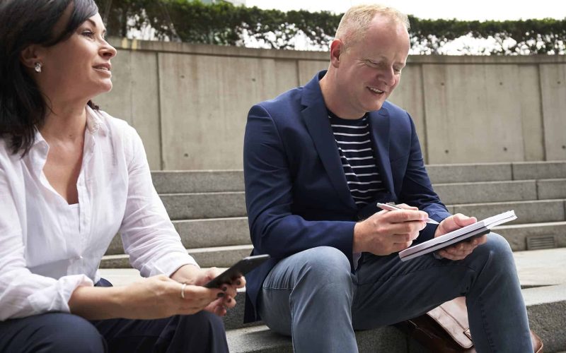 woman and man having a discussion while sitting on steps