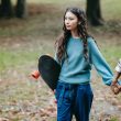 hispanic woman with longboard walking with crop partner