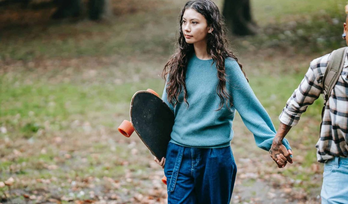 hispanic woman with longboard walking with crop partner