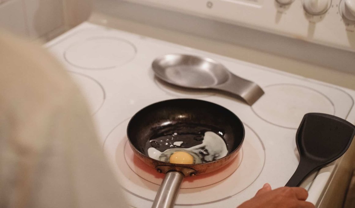 crop person cooking fried eggs