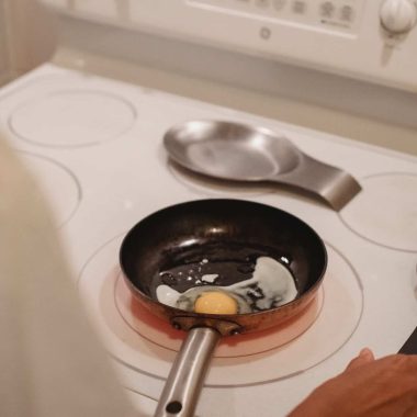 crop person cooking fried eggs