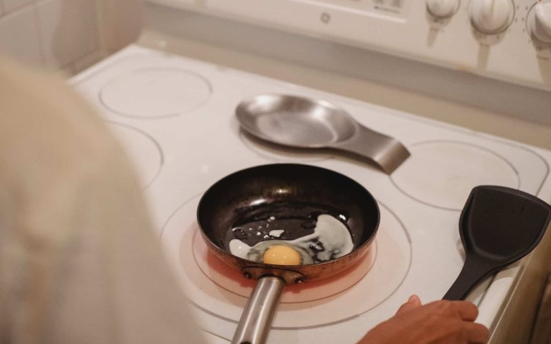 crop person cooking fried eggs