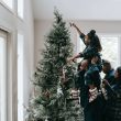 a girl putting a christmas star on a christmas tree