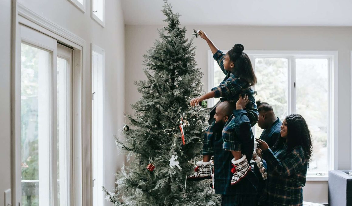 a girl putting a christmas star on a christmas tree