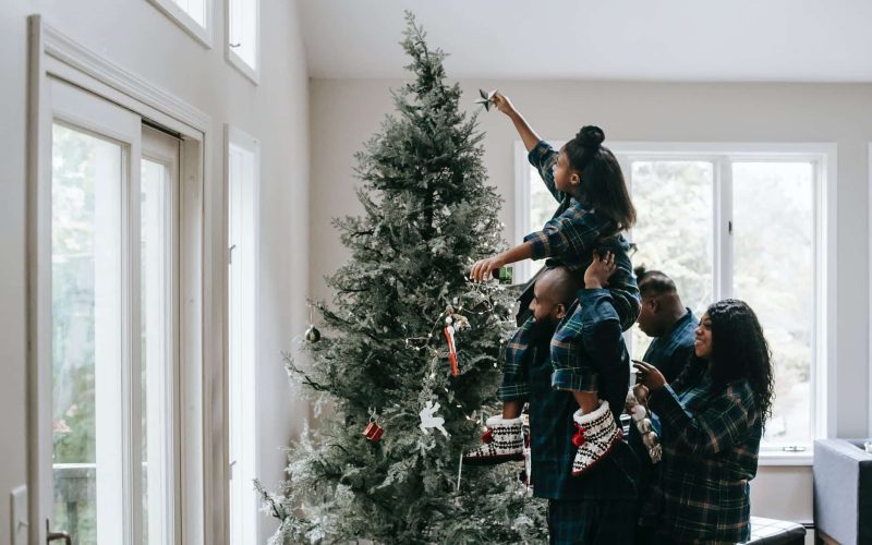 a girl putting a christmas star on a christmas tree