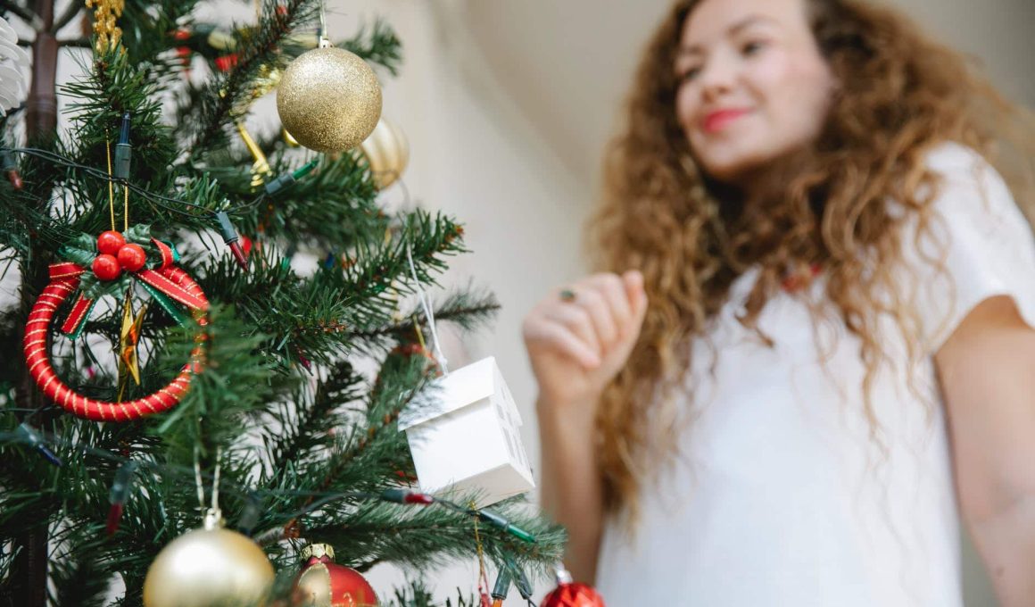 young woman standing near christmas tree decorated with baubles