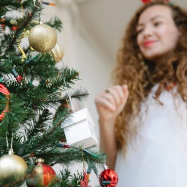 young woman standing near christmas tree decorated with baubles