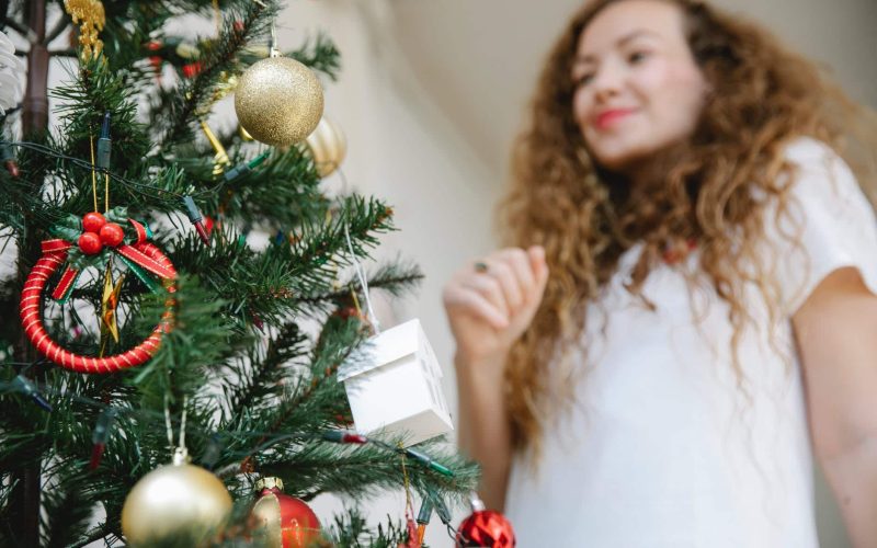 young woman standing near christmas tree decorated with baubles