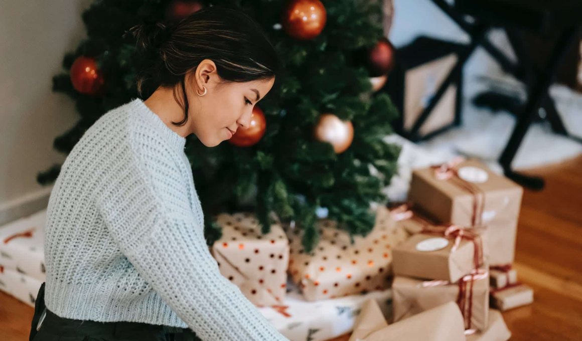 ethnic woman with pile of present boxes against christmas tree