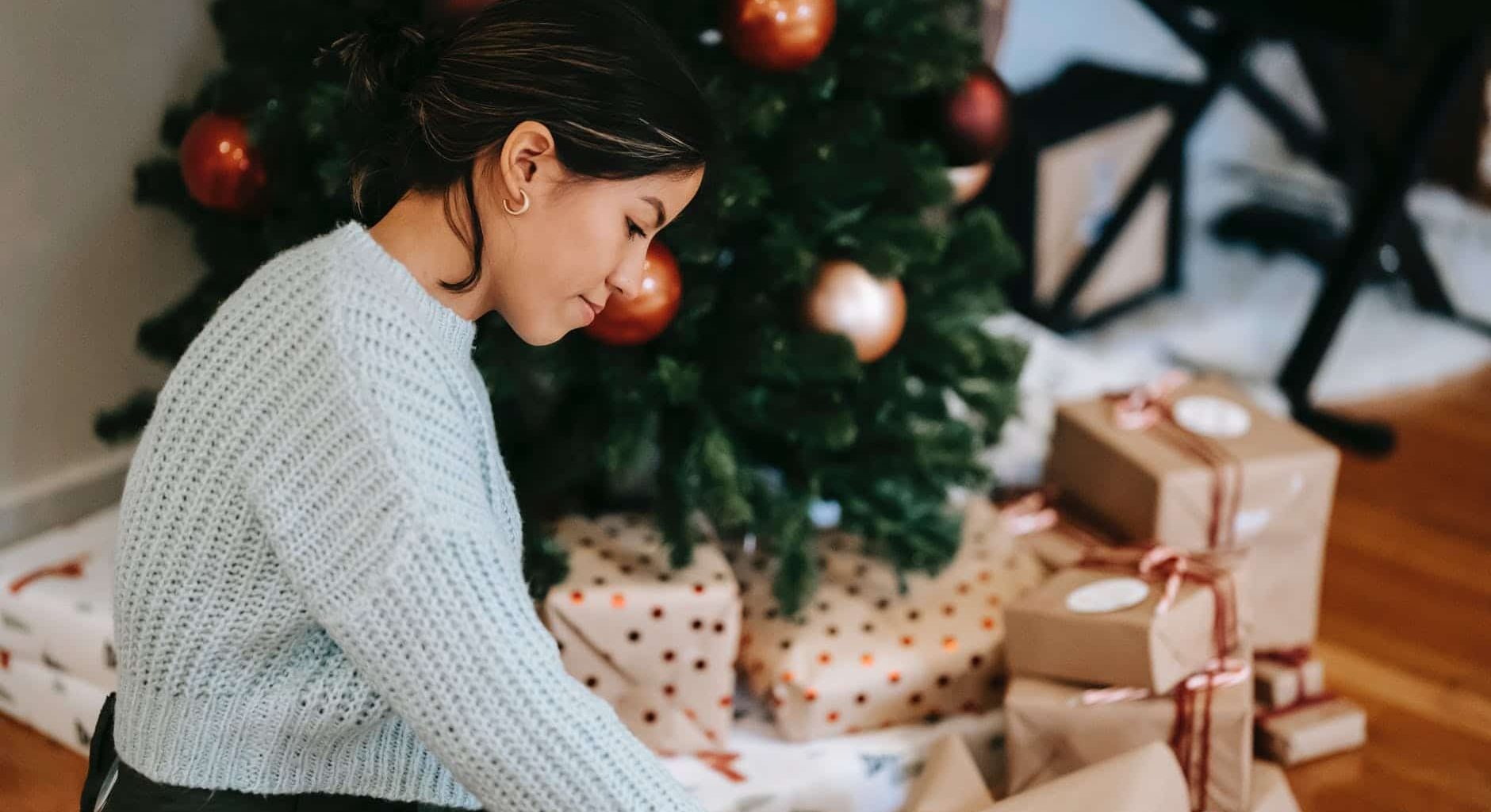 ethnic woman with pile of present boxes against christmas tree