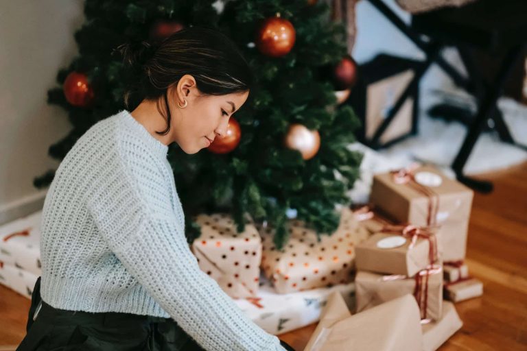 ethnic woman with pile of present boxes against christmas tree