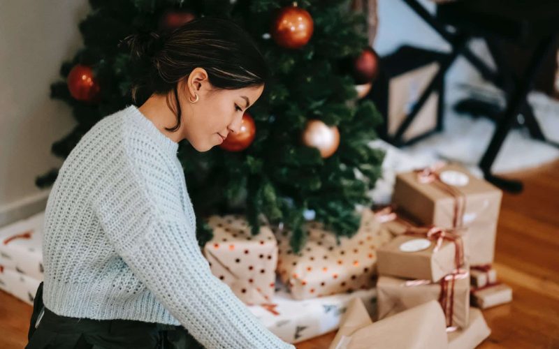 ethnic woman with pile of present boxes against christmas tree