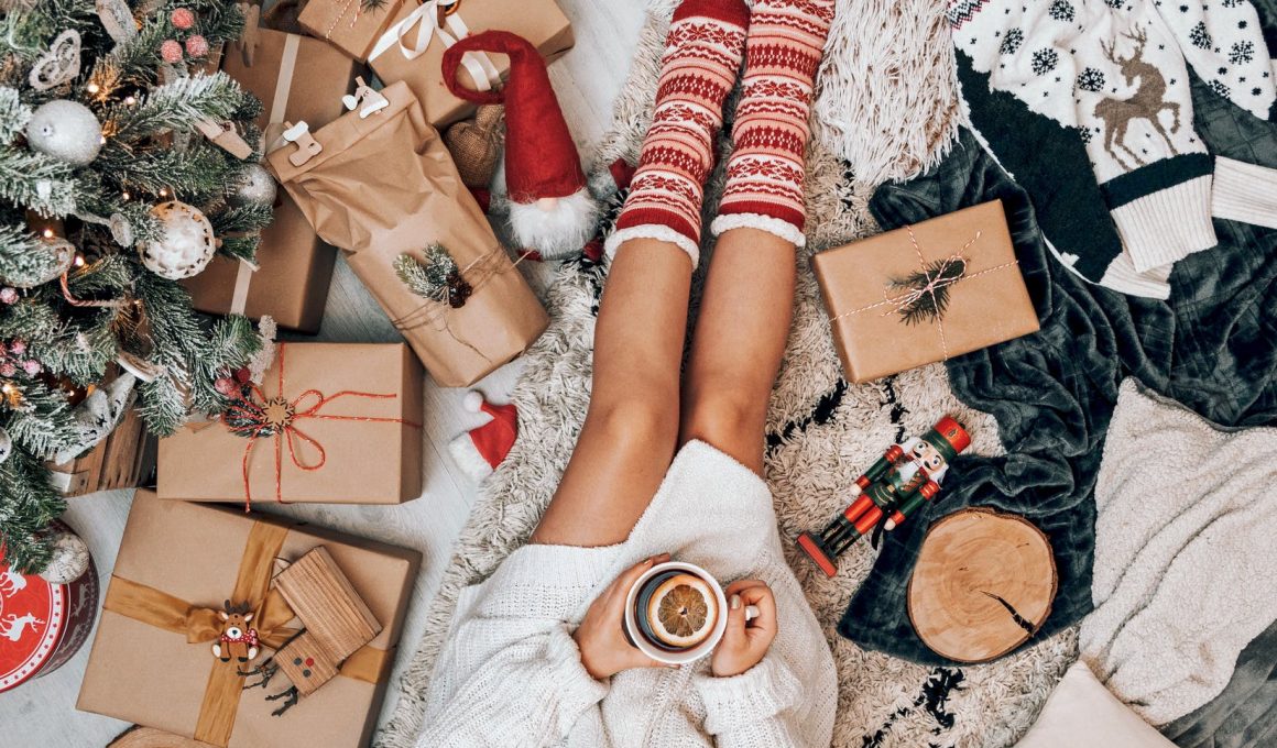 crop faceless woman drinking tea and sitting near christmas tree