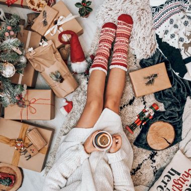 crop faceless woman drinking tea and sitting near christmas tree