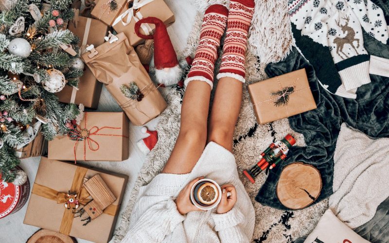 crop faceless woman drinking tea and sitting near christmas tree