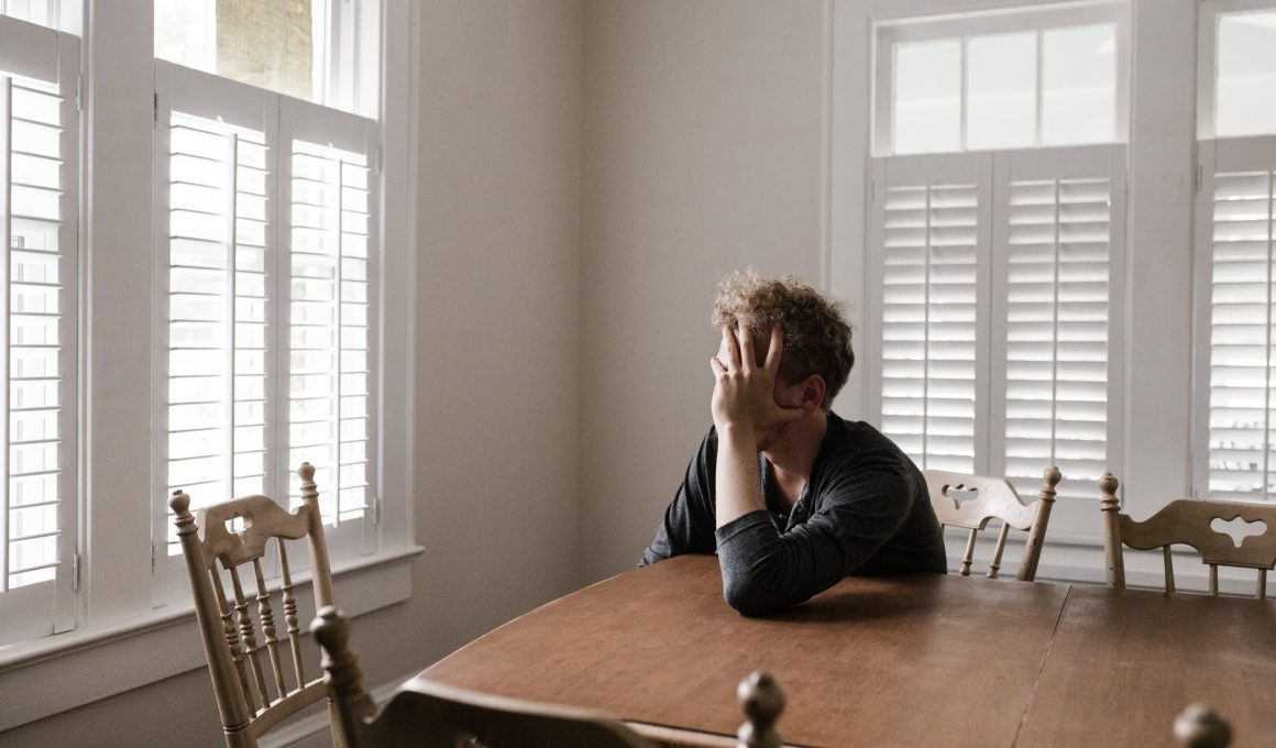 photo of man leaning on wooden table