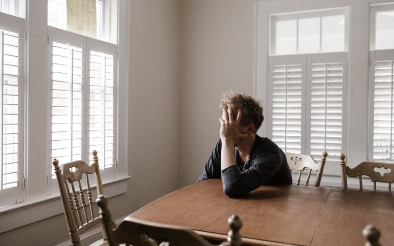 photo of man leaning on wooden table