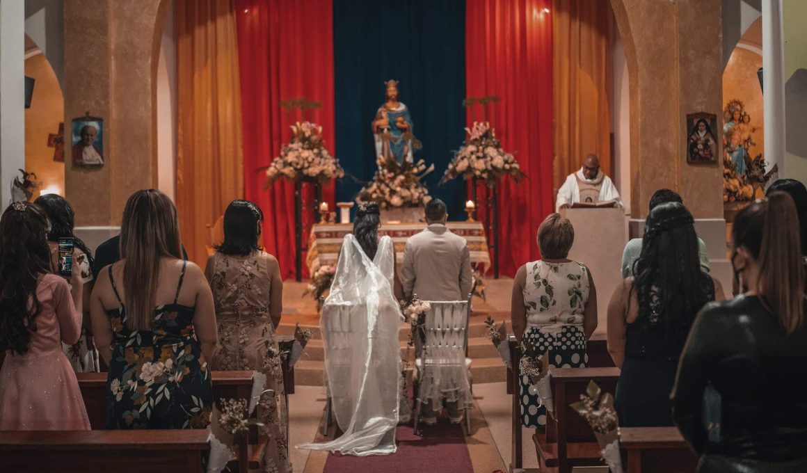 unrecognizable newlyweds and guests standing in church hall