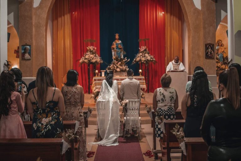 unrecognizable newlyweds and guests standing in church hall
