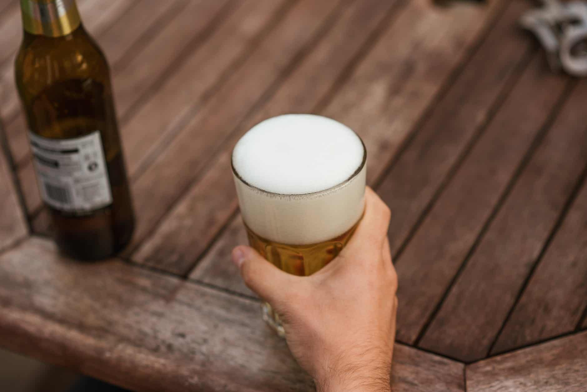 man with glass of foamy beer at table