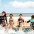 woman and three children playing water