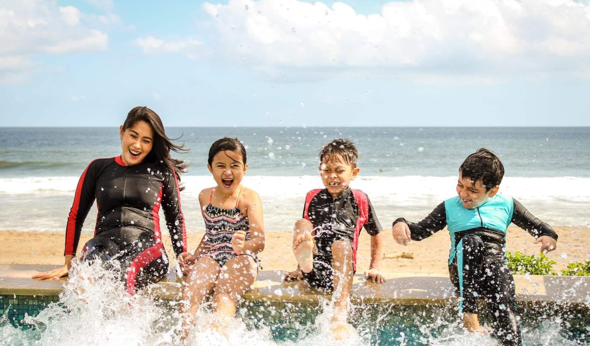 woman and three children playing water