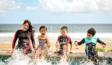 woman and three children playing water