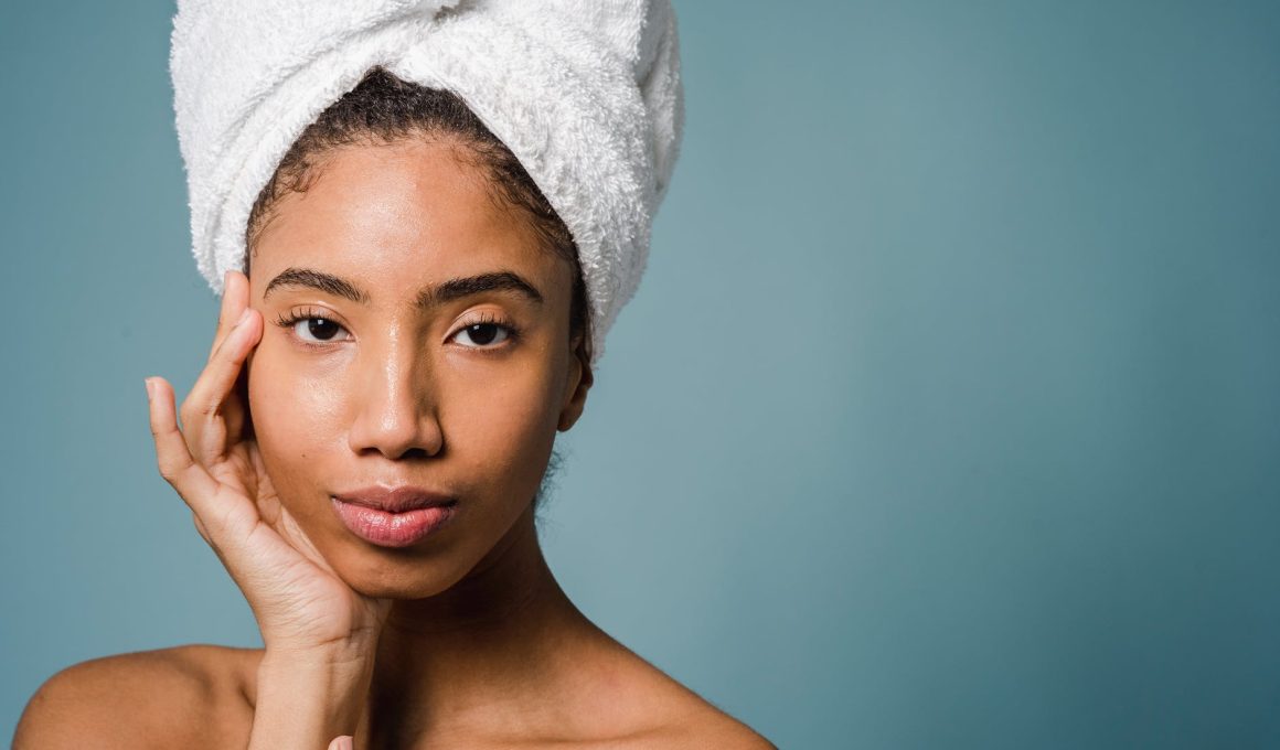 calm young ethnic woman with perfect skin touching face after shower