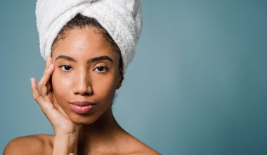 calm young ethnic woman with perfect skin touching face after shower
