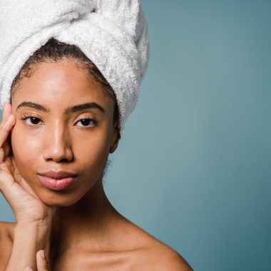 calm young ethnic woman with perfect skin touching face after shower