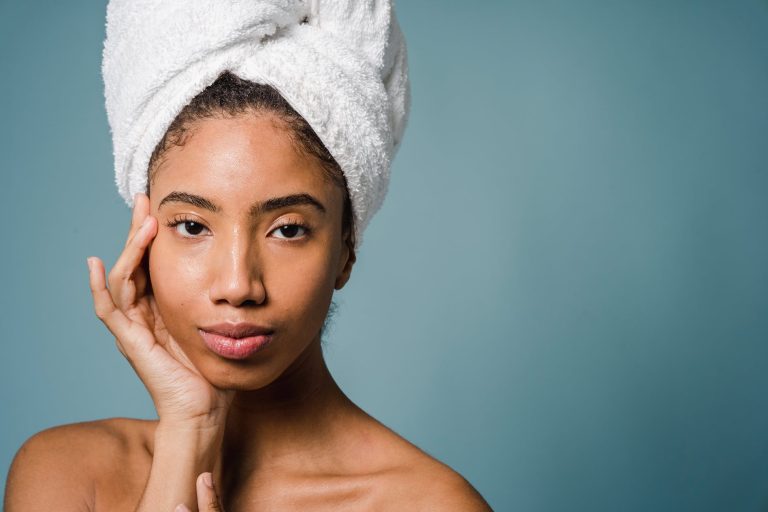calm young ethnic woman with perfect skin touching face after shower