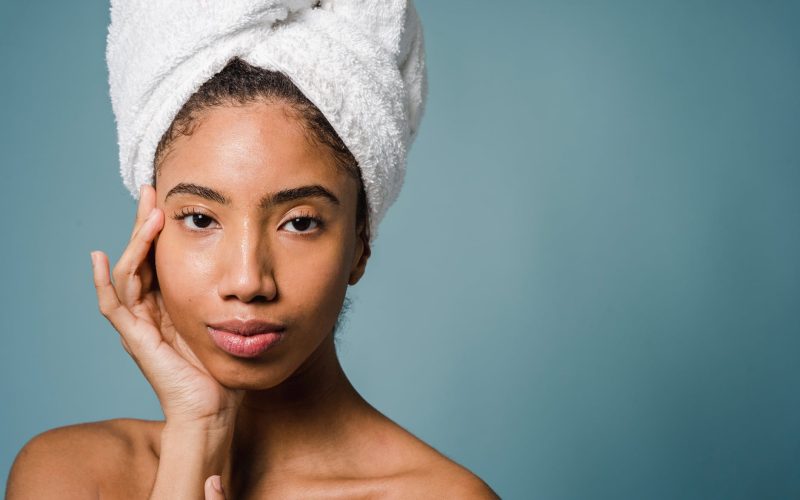 calm young ethnic woman with perfect skin touching face after shower