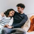 smiling multiracial couple hugging on couch