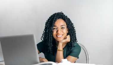 happy ethnic woman sitting at table with laptop
