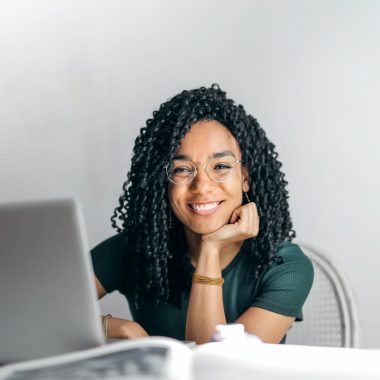 happy ethnic woman sitting at table with laptop