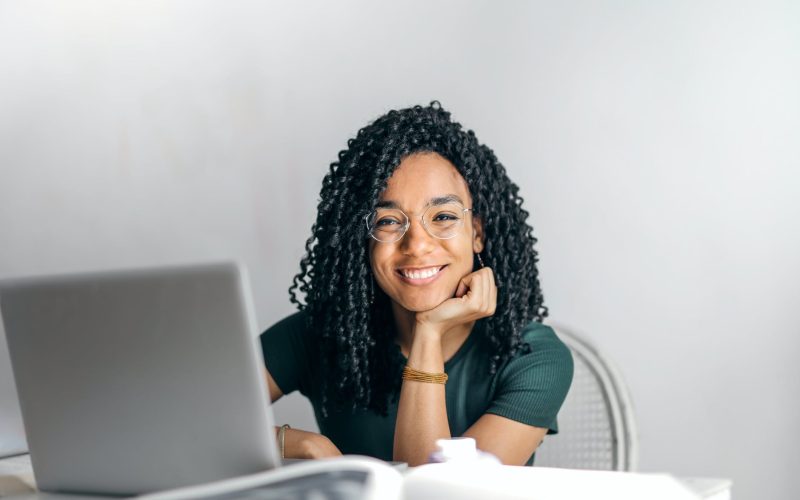 happy ethnic woman sitting at table with laptop